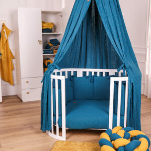 Lettino montessori Venere con baldacchino e completo piumone e paracolpi in mussola Shiny ottanio, treccia in mussola senape su tappeto giochi termico, con armadio per neonato sullo sfondo